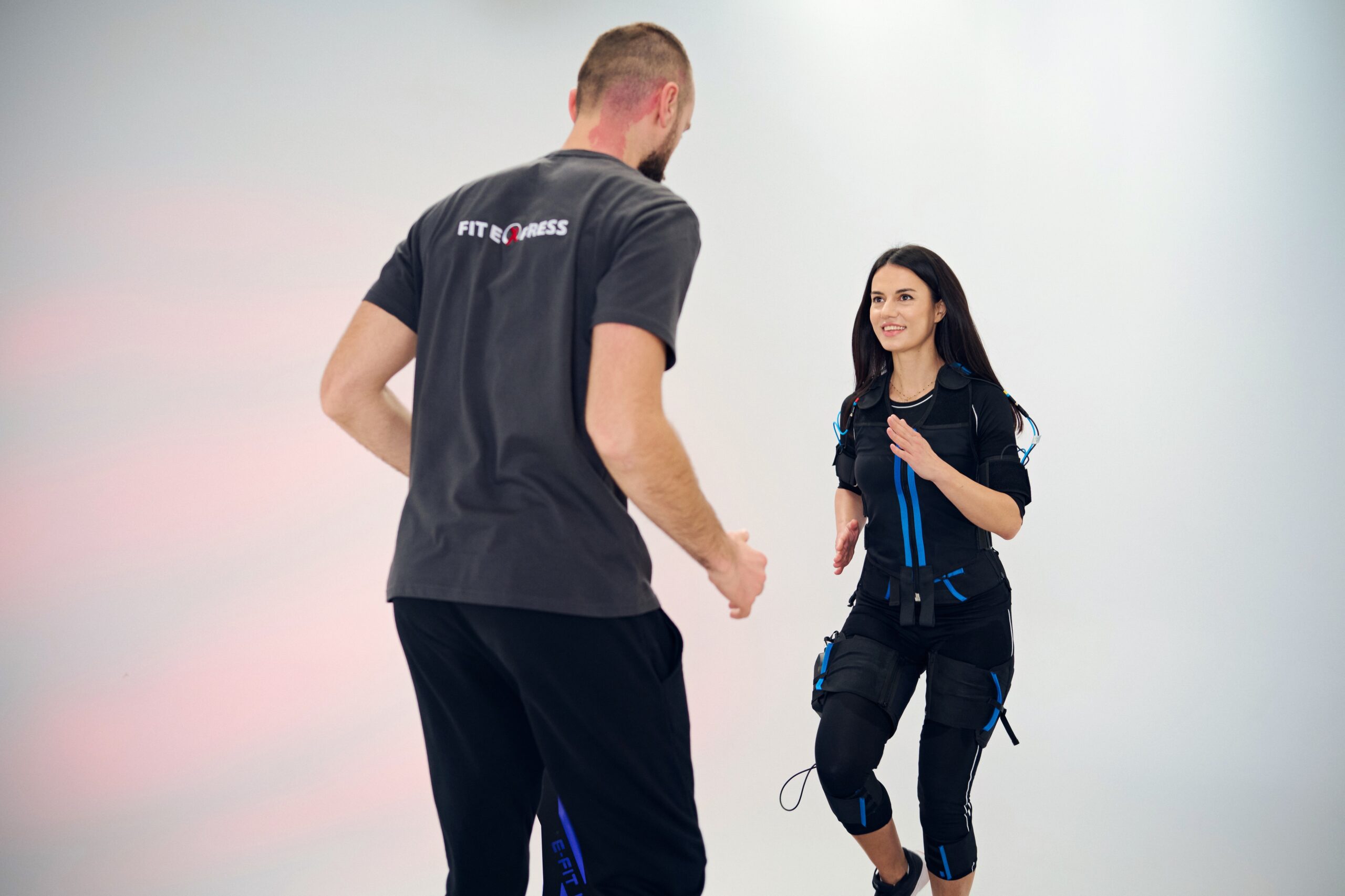 A man standing with an EMS device working out pose.